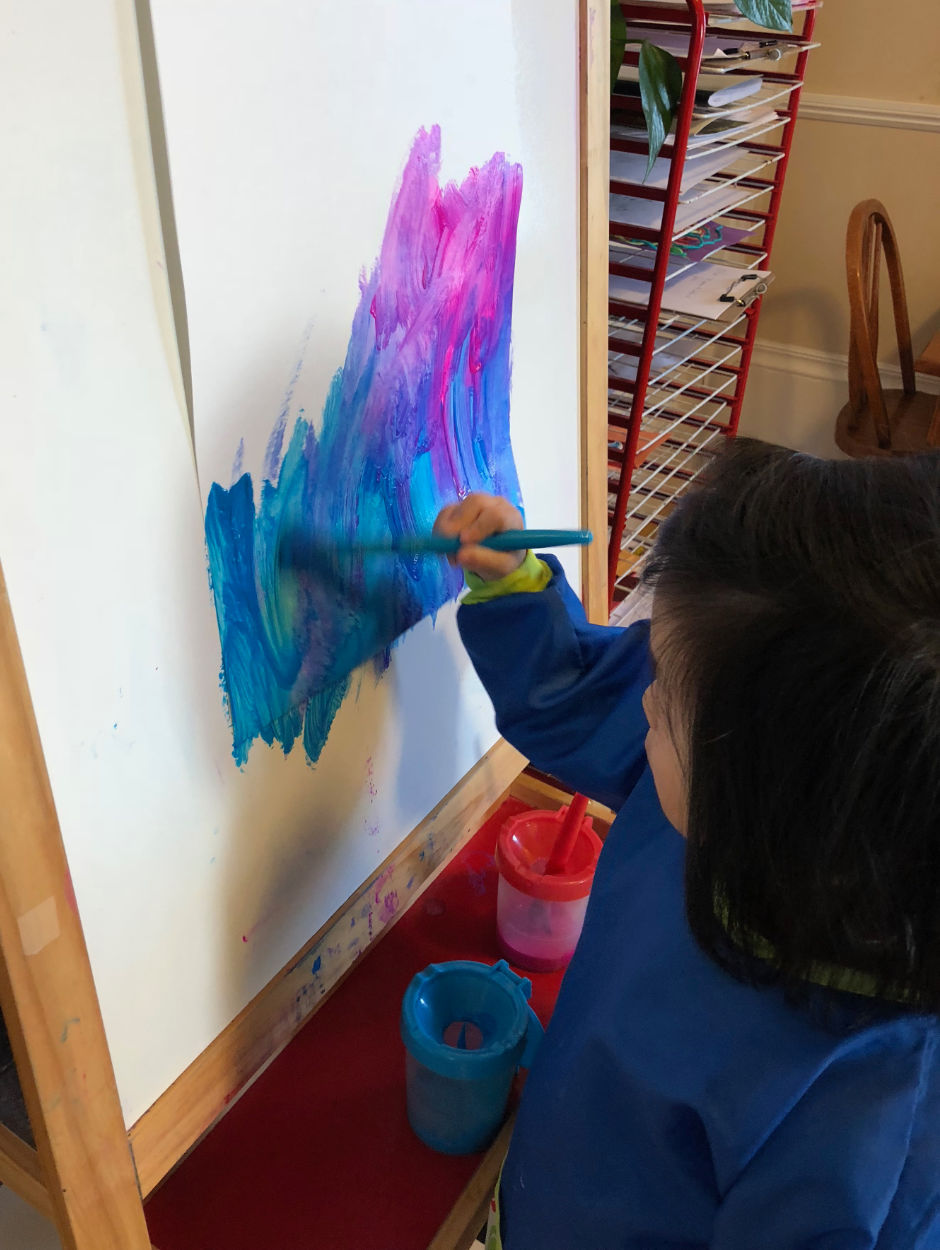 Child painting with blue and purple paint